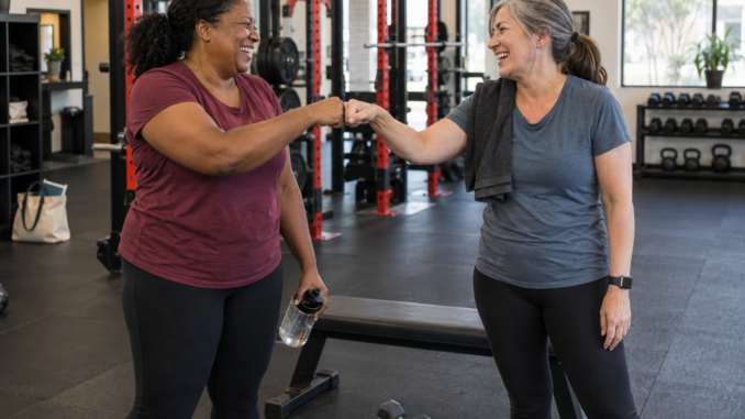 Two friends sharing a smile and fist bump between sets in a strength gym.