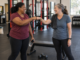 Two friends sharing a smile and fist bump between sets in a strength gym.