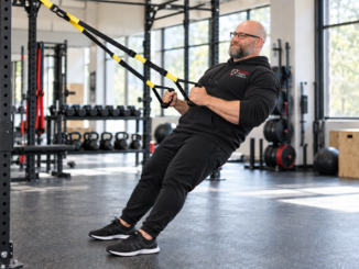 Justin Stead holding suspension trainer handles in a gym for the TRX workout after 40