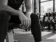 Black and white image of a person resting on a gym bench between sets.